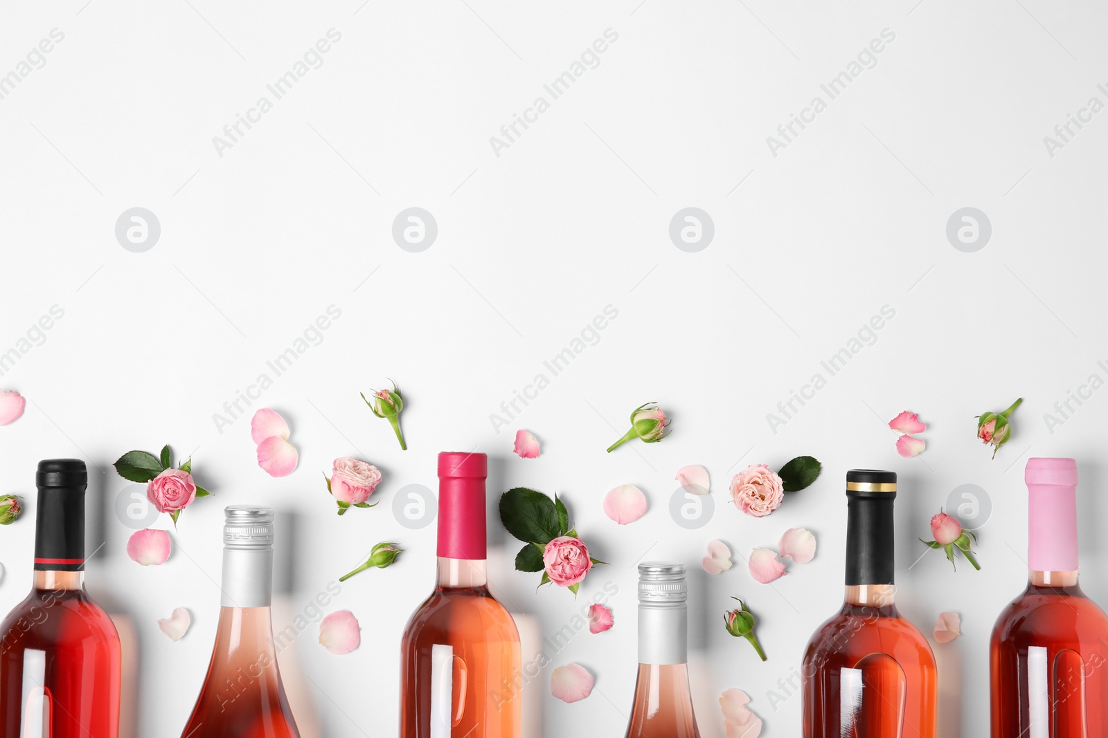 Photo of Composition with bottles of delicious rose wine on white background, top view