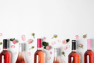 Composition with bottles of delicious rose wine on white background, top view