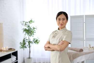 Photo of Portrait of young Asian masseuse in spa salon. Space for text