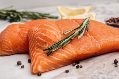 Photo of Marble board with tasty salmon fillet on table, closeup