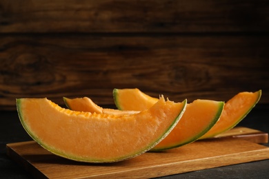Photo of Slices of tasty fresh melon on black table, closeup