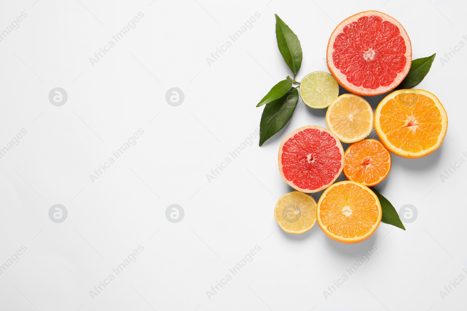 Photo of Different citrus fruits with fresh leaves on white background, top view. Space for text