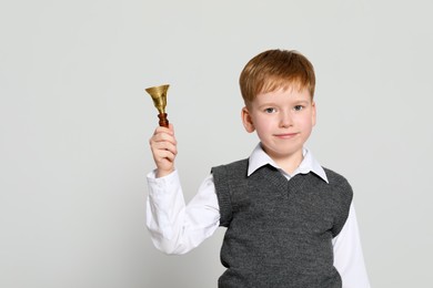 Photo of Pupil with school bell on light grey background. Space for text