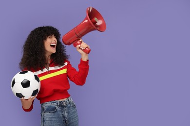 Happy fan holding soccer ball and using megaphone on violet background, space for text