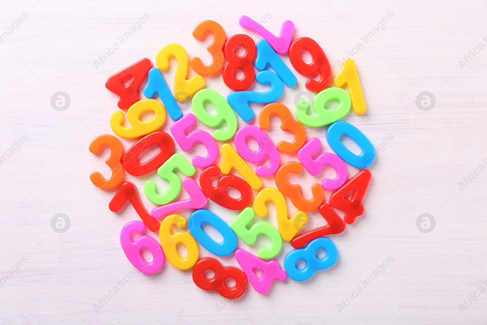 Photo of Colorful numbers on white wooden school desk, top view