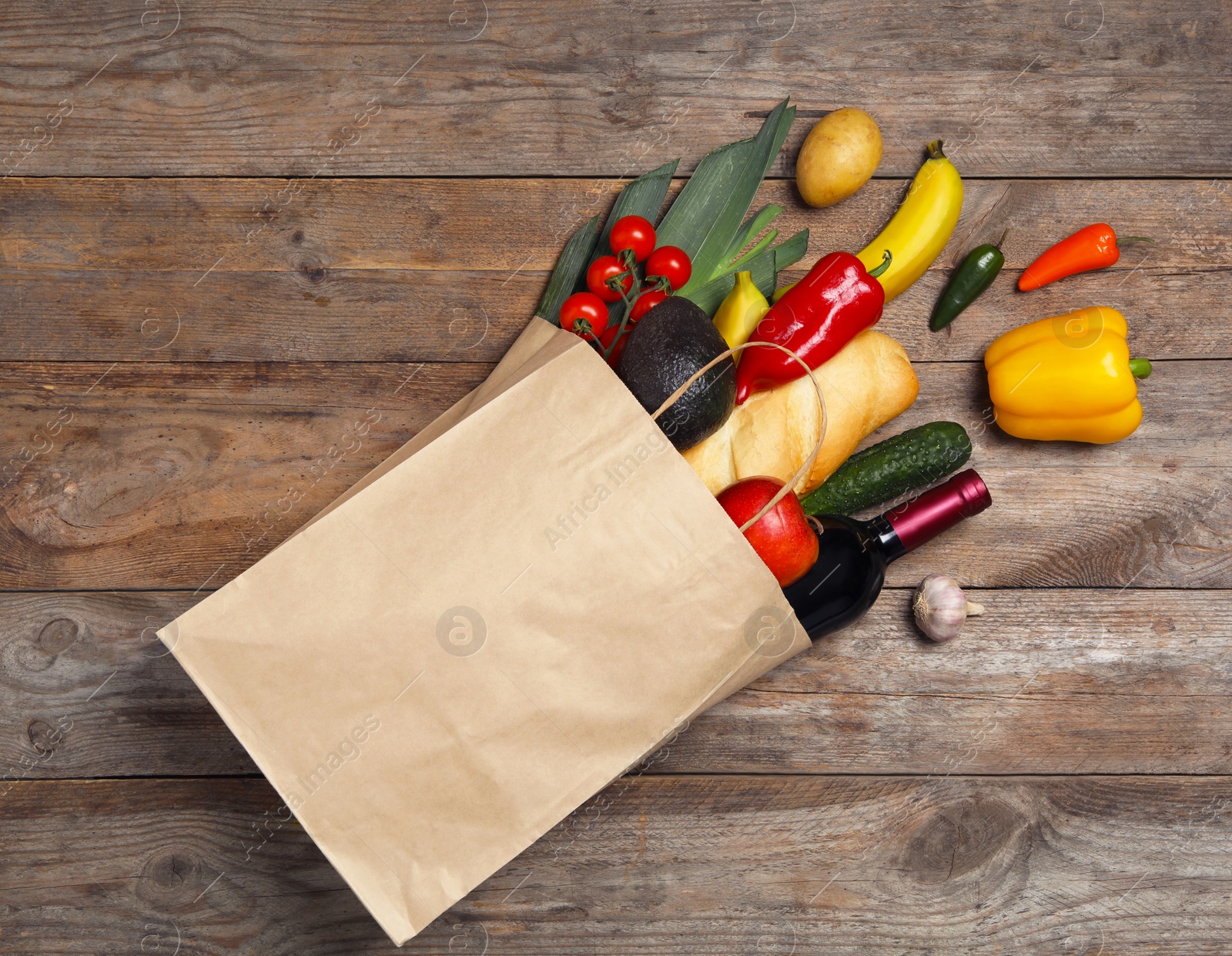 Photo of Shopping paper bag with different groceries on wooden background, flat lay