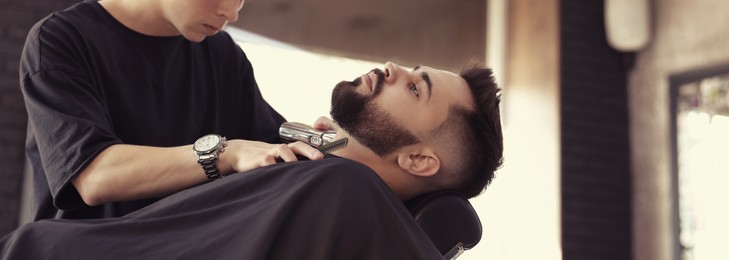 Professional hairdresser working with bearded client in barbershop. Banner design