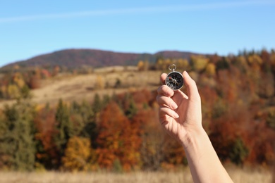 Photo of Traveler searching direction with compass in wilderness, closeup. Space for text