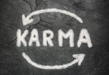 Photo of Drawn circle and word Karma made of sea salt on dark background, flat lay