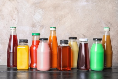 Bottles with different drinks on table against color background