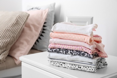 Stack of stylish child clothes on table indoors