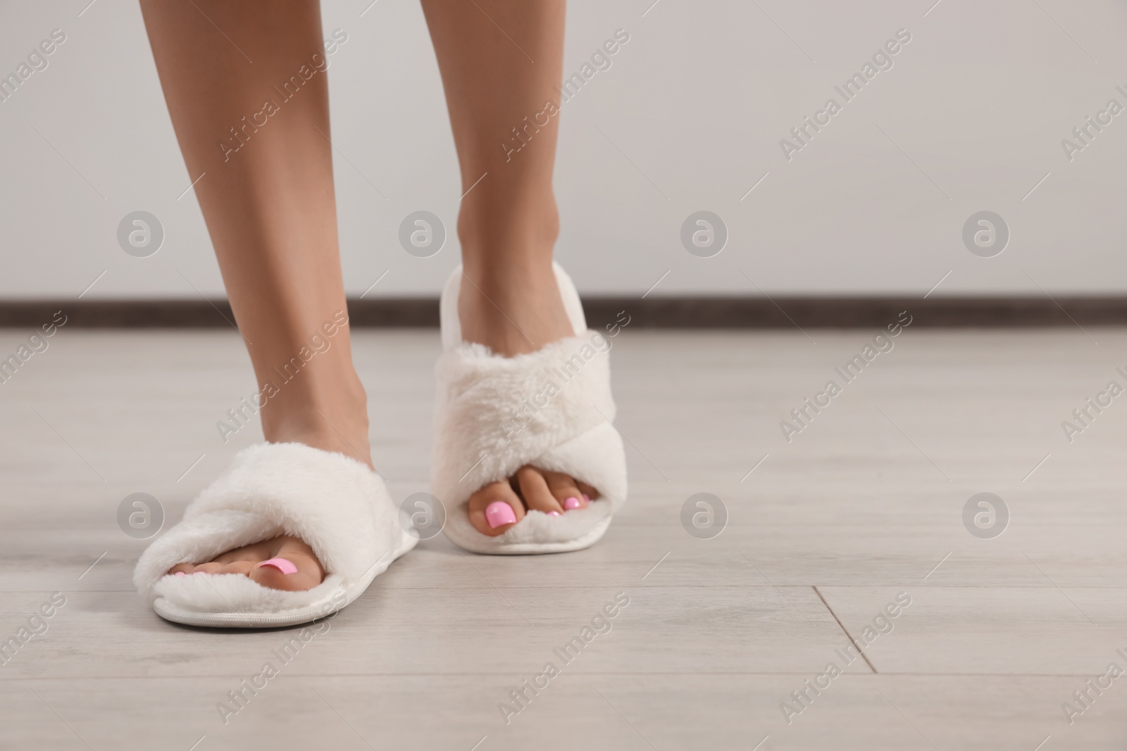 Photo of Woman wearing white soft slippers indoors, closeup. Space for text