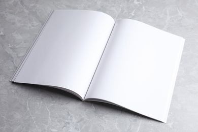 Photo of Blank open book on light grey marble background. Mock up for design