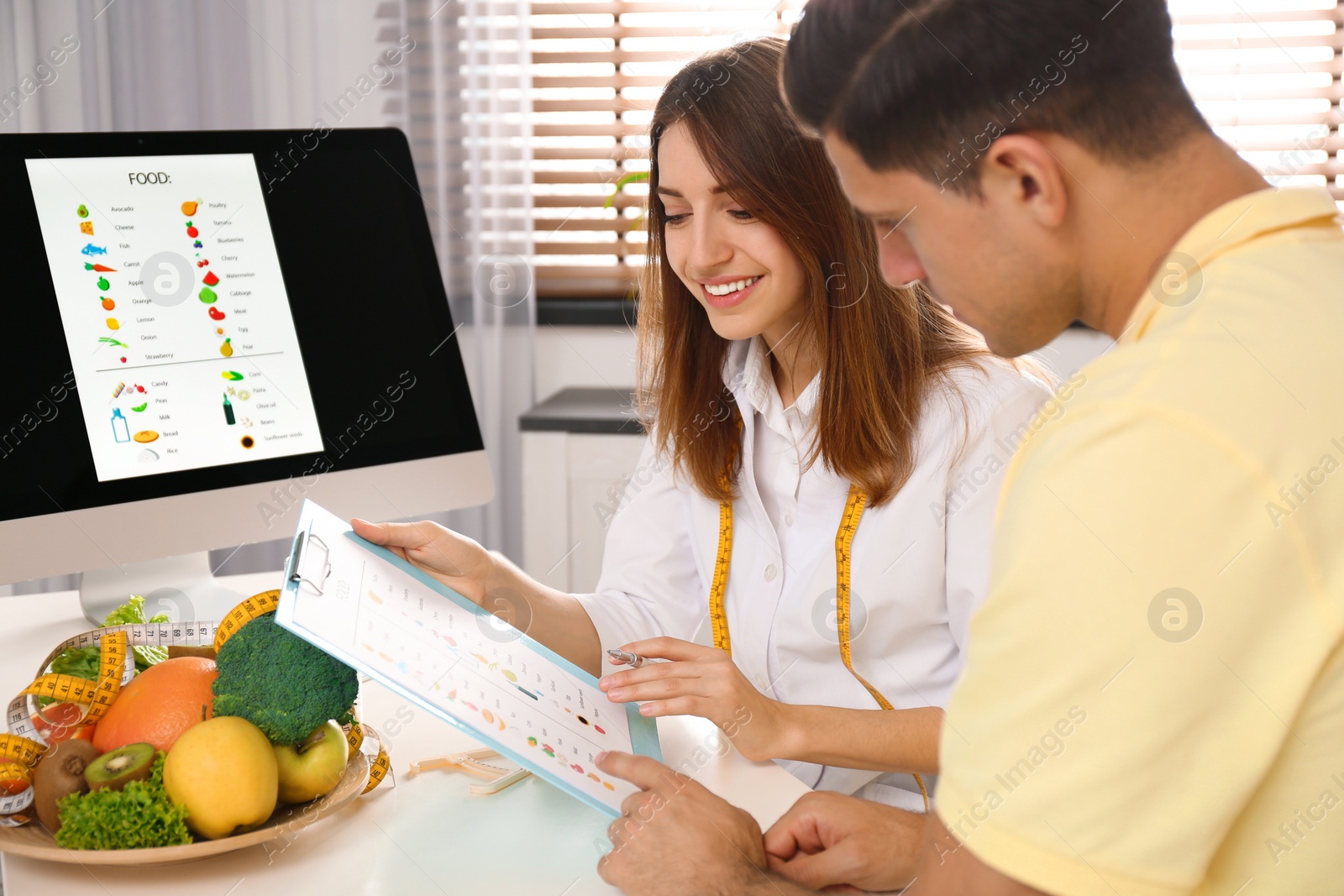 Photo of Young nutritionist consulting patient at table in clinic