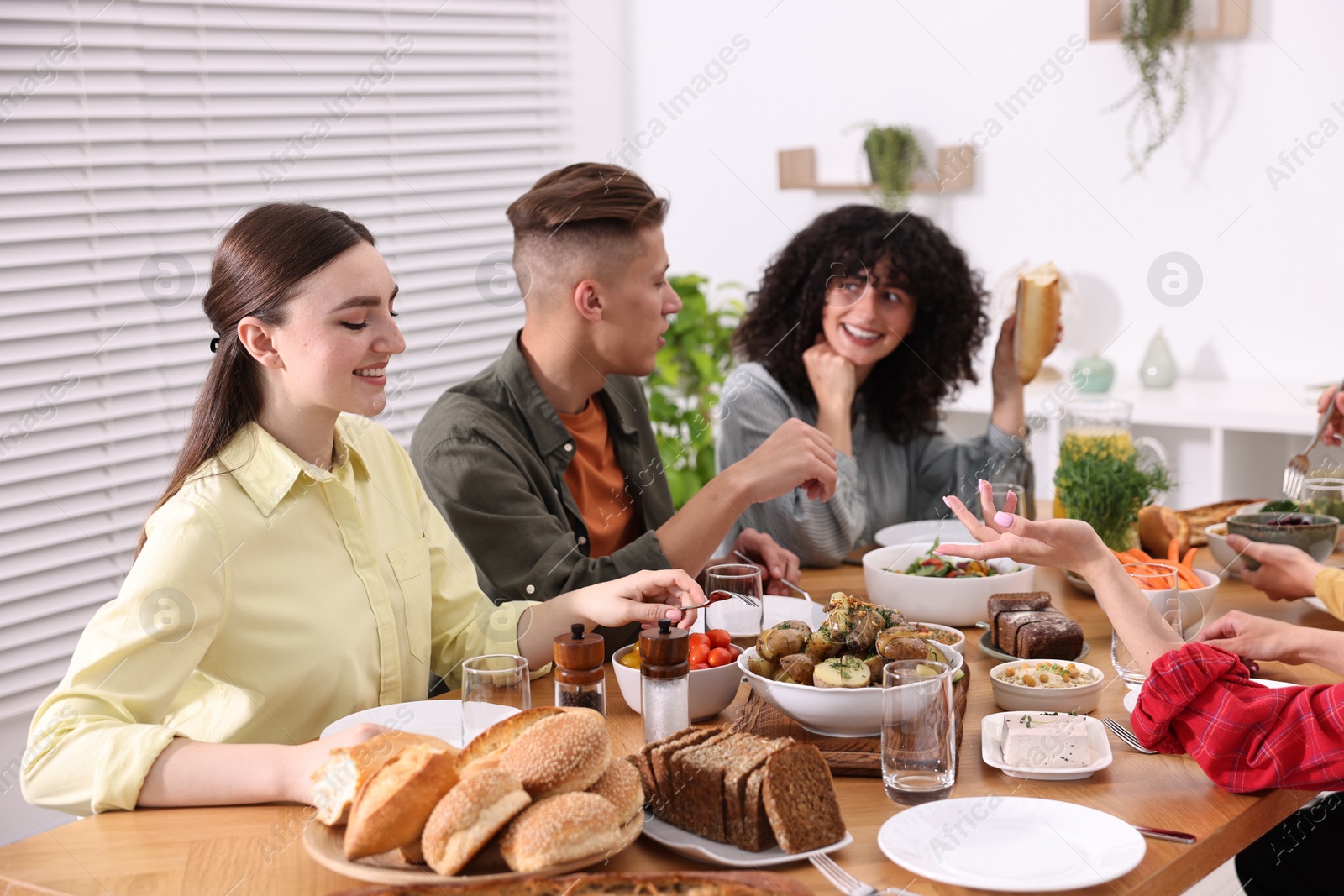 Photo of Friends eating vegetarian food at wooden table indoors