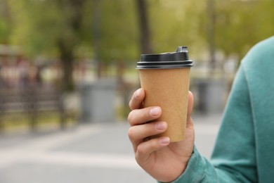 Photo of Man with takeaway coffee cup on city street, closeup. Space for text