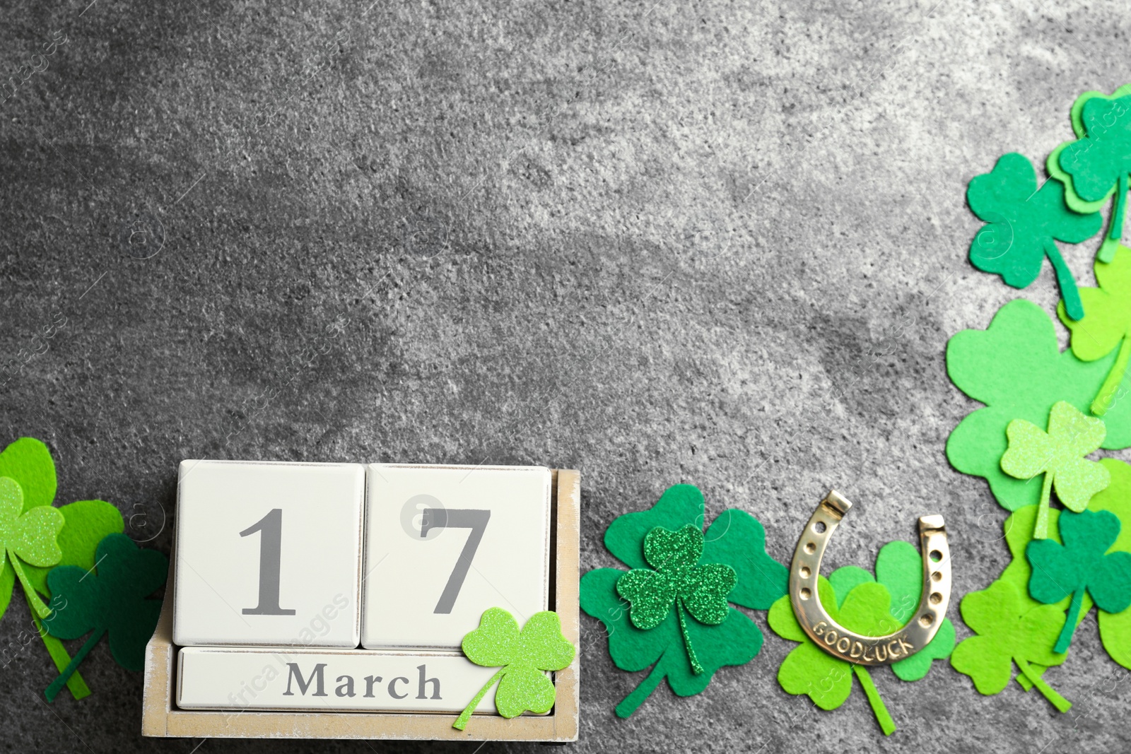 Photo of Flat lay composition with clover leaves and block calendar on grey stone background, space for text. St. Patrick's day