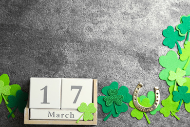 Photo of Flat lay composition with clover leaves and block calendar on grey stone background, space for text. St. Patrick's day