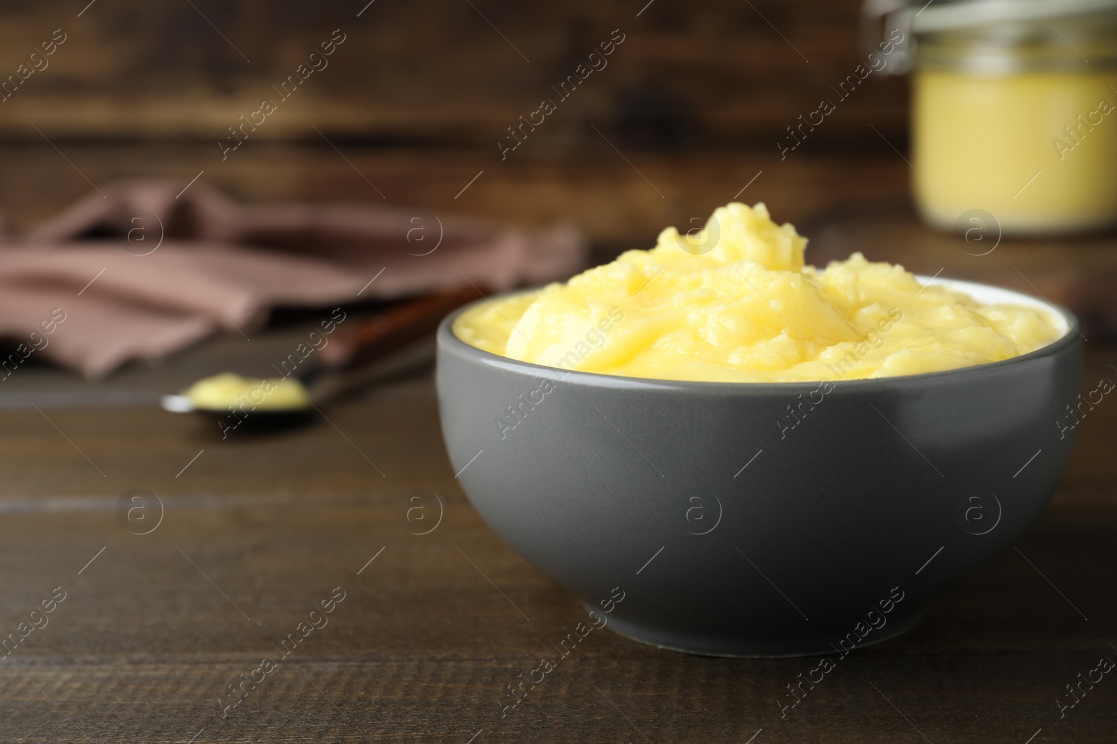 Photo of Bowl of Ghee butter on wooden table, closeup. Space for text