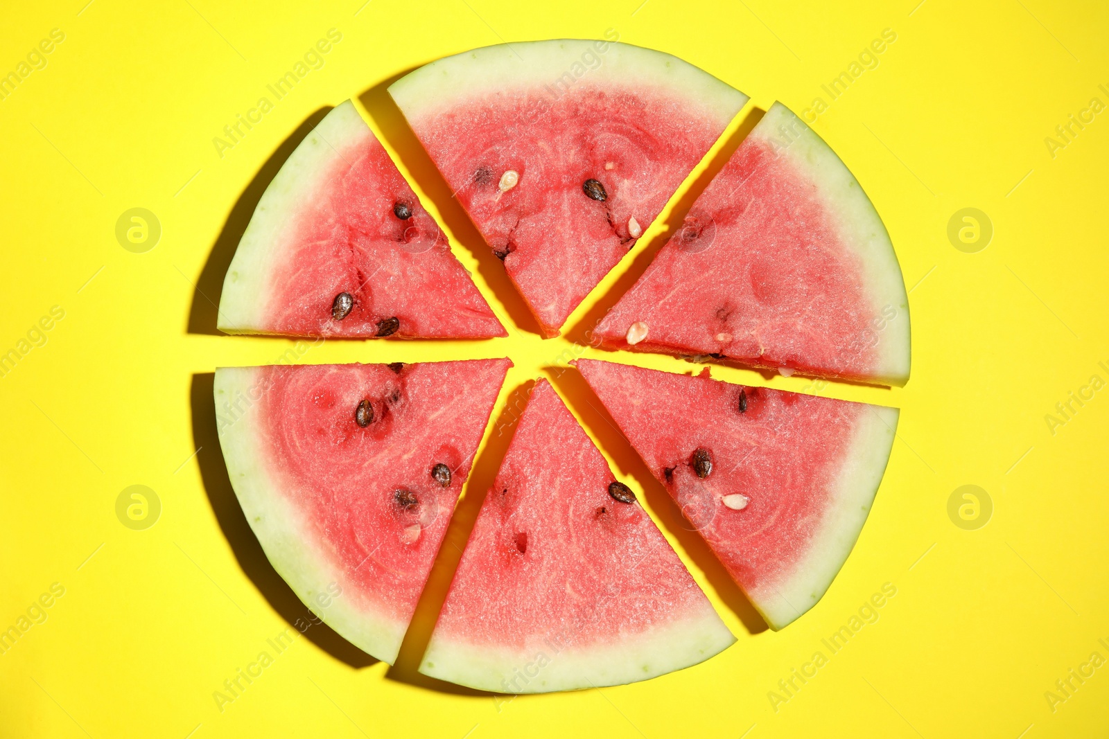 Photo of Watermelon slices on yellow background, flat lay