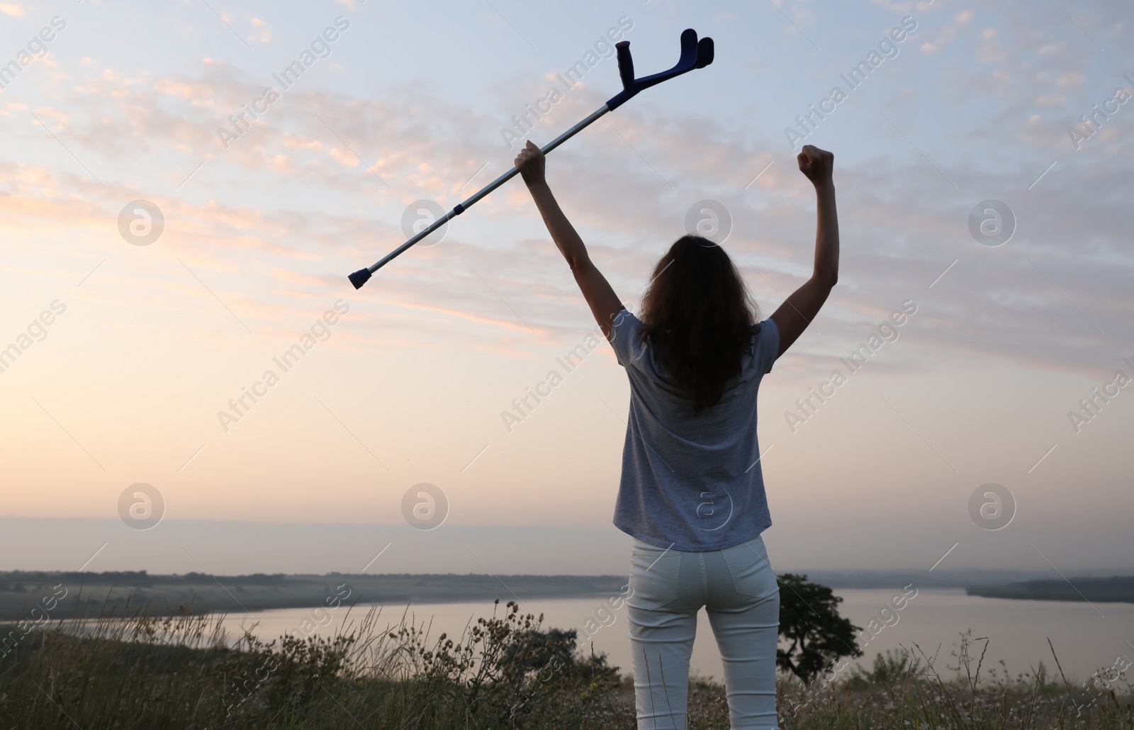 Photo of Woman holding elbow crutch outdoors at sunrise, back view. Healing miracle