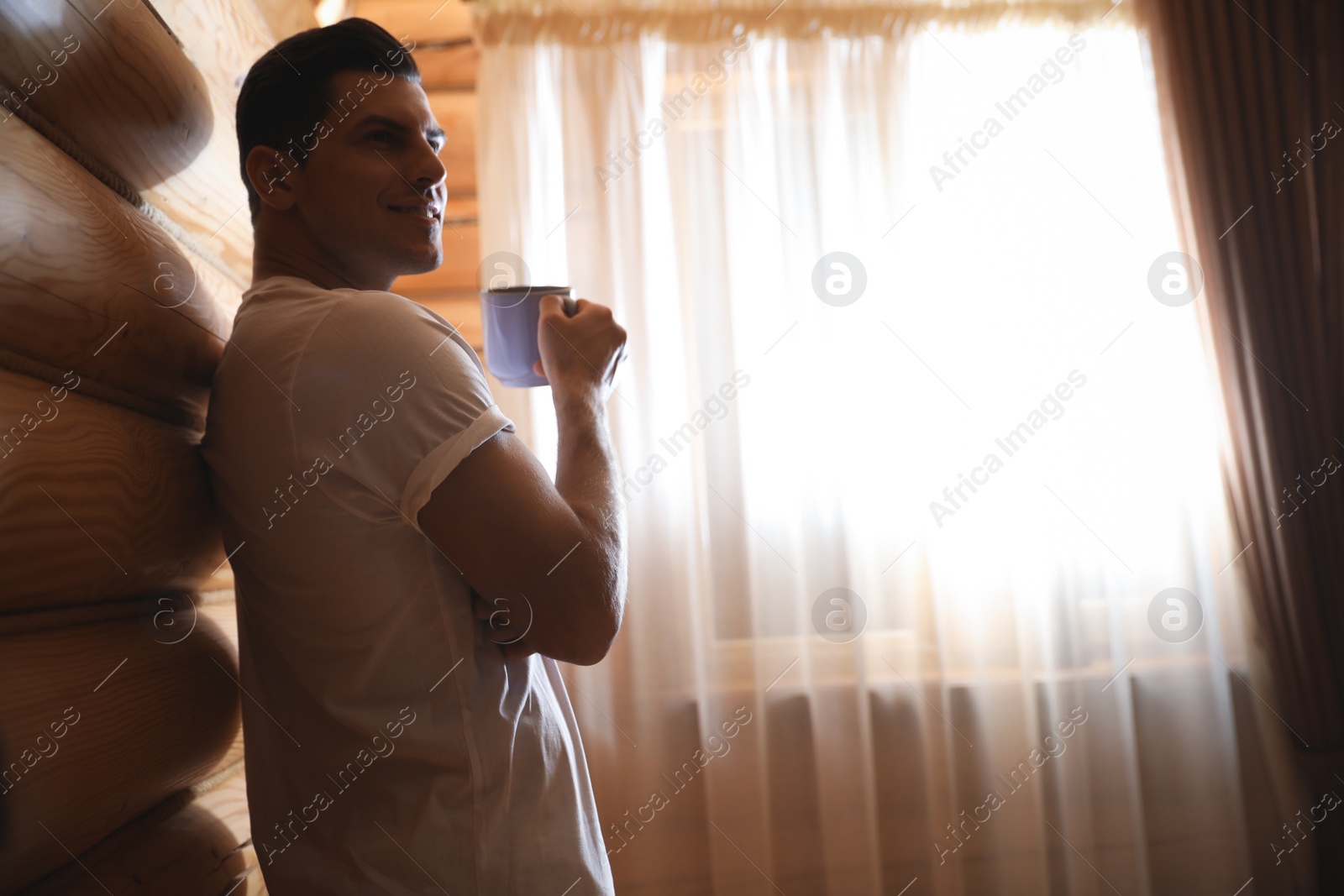 Photo of Man with drink near window indoors. Lazy morning