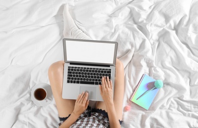 Photo of Top view of woman with laptop sitting on bed, closeup. Mockup for design