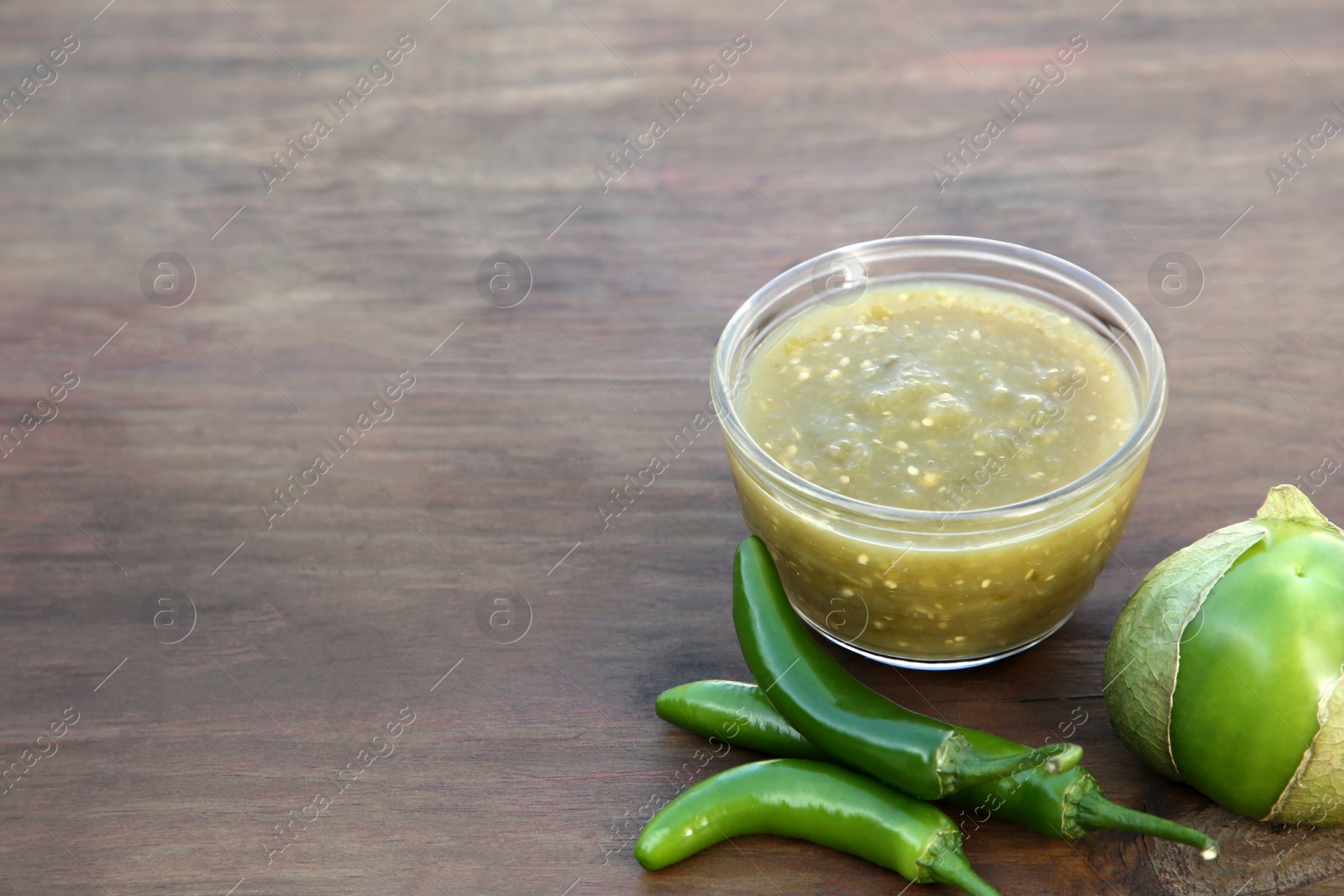 Photo of Tasty salsa sauce and ingredients on wooden table, closeup. Space for text