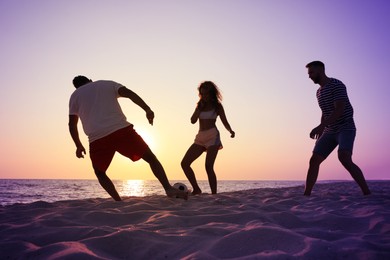 Photo of Friends playing football on beach at sunset