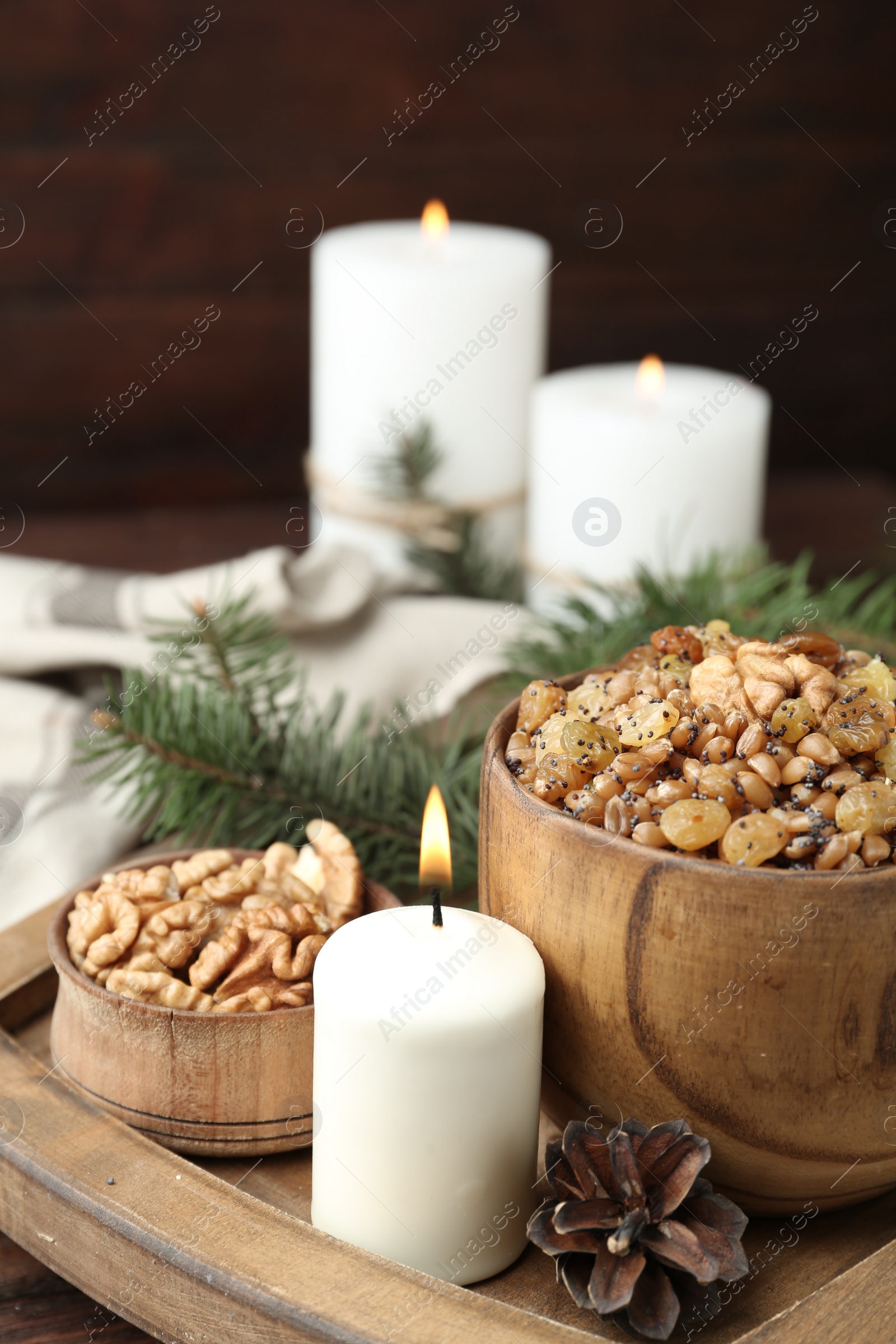 Photo of Traditional Christmas slavic dish kutia and burning candle on wooden tray, closeup. Space for text