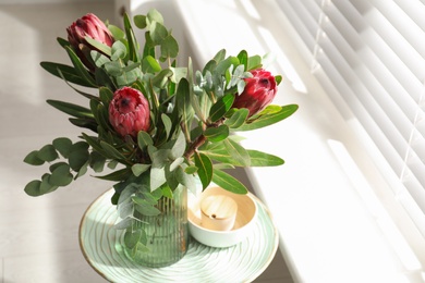 Vase with bouquet of beautiful Protea flowers on table indoors