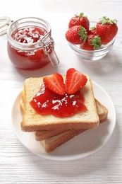 Photo of Tasty toast bread with strawberry jam and fresh berries on light background