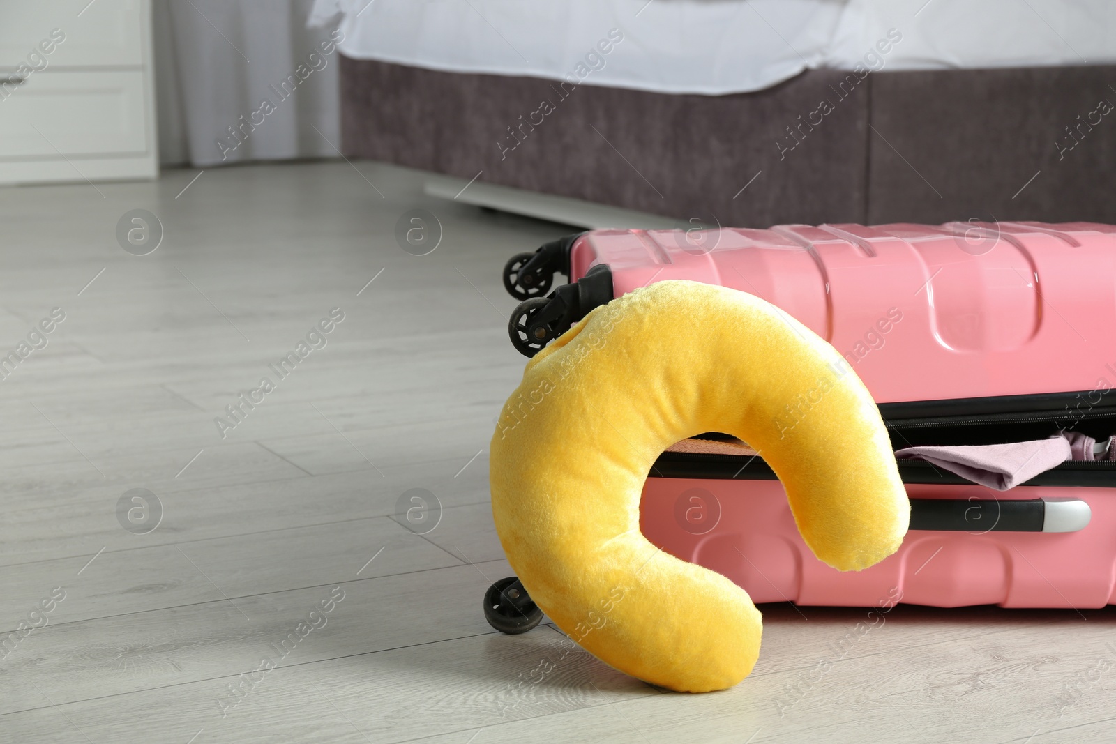 Photo of Suitcase with clothes and travel pillow in bedroom