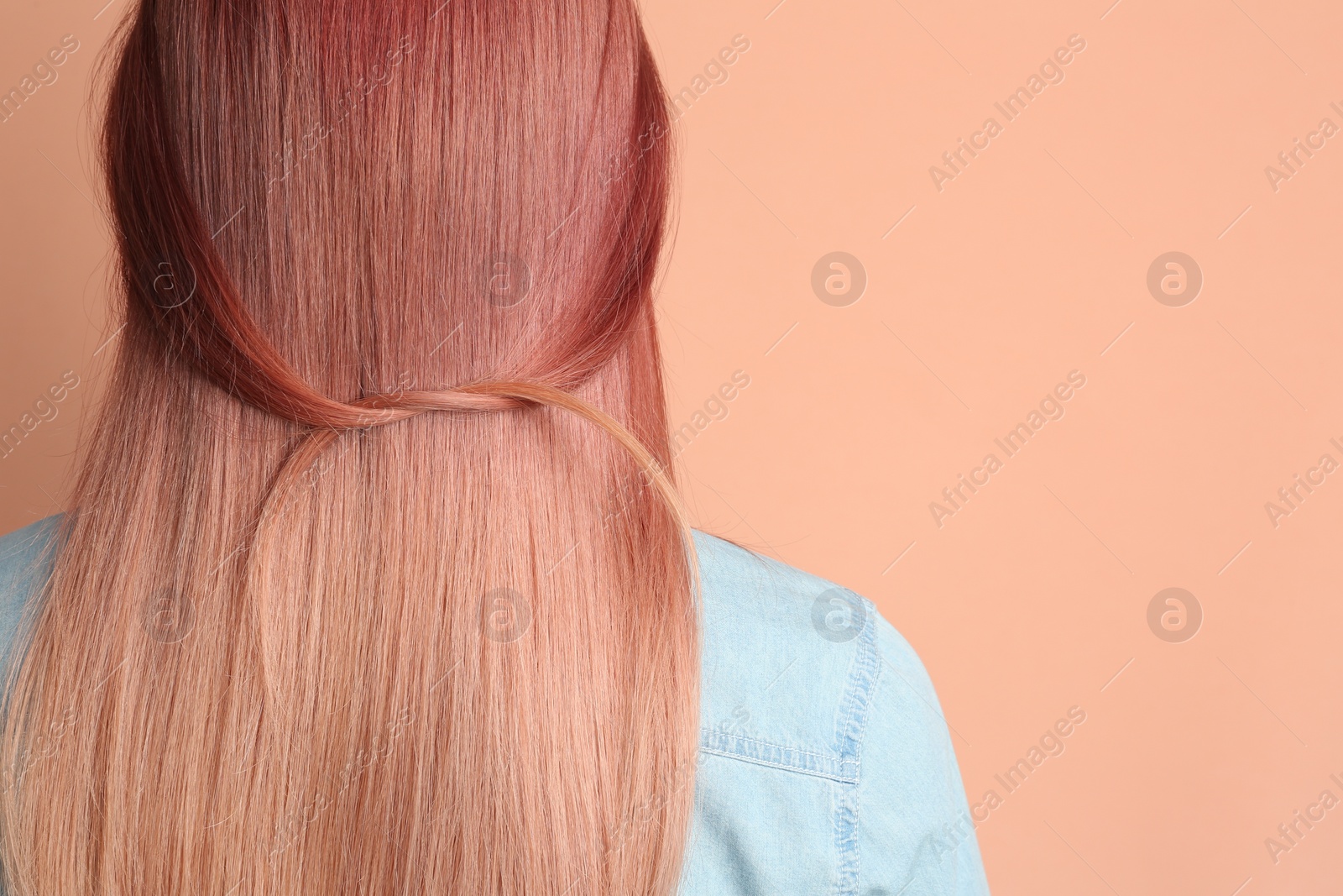 Photo of Woman with bright dyed hair on pale pink background, back view. Space for text