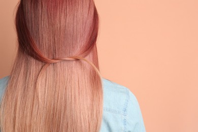Photo of Woman with bright dyed hair on pale pink background, back view. Space for text