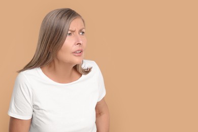 Photo of Portrait of surprised senior woman on beige background, space for text