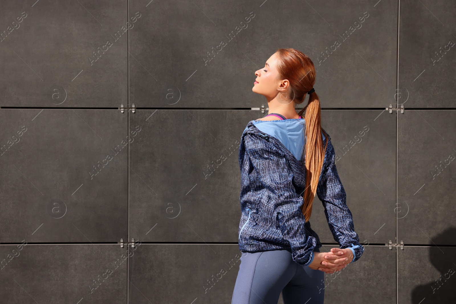 Photo of Beautiful woman in gym clothes doing exercises on street, space for text