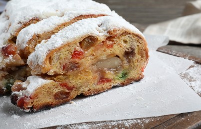 Photo of Traditional Christmas Stollen with icing sugar on wooden board, closeup