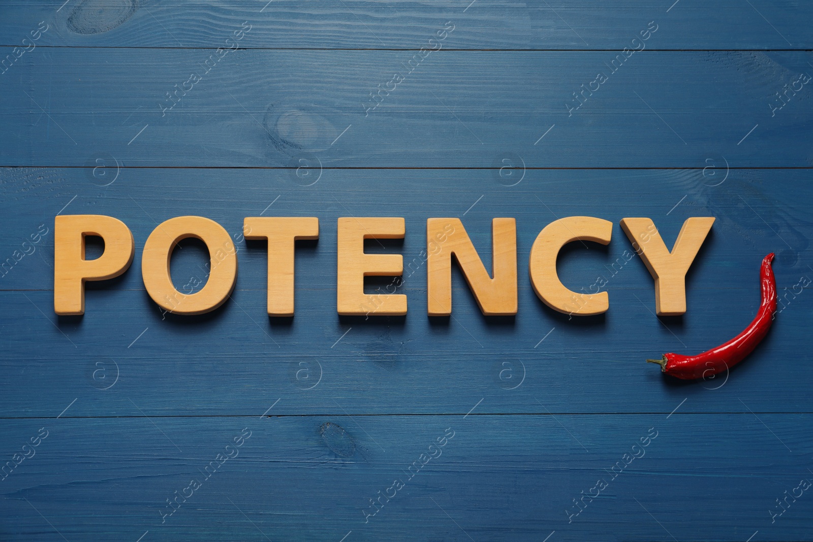 Photo of Word Potency made of letters and chili pepper on blue wooden table, flat lay