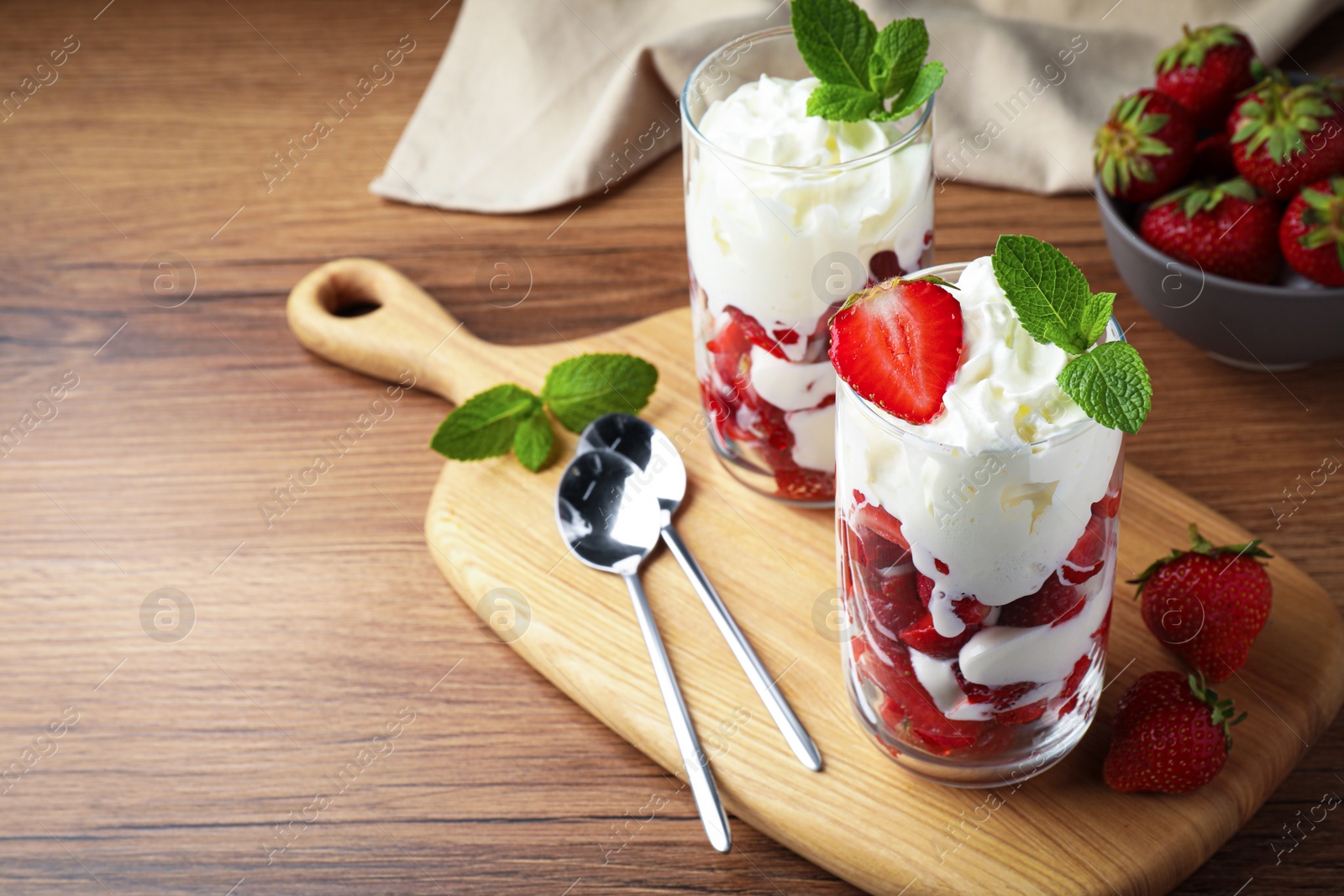 Photo of Delicious strawberries with whipped cream served on wooden table. Space for text