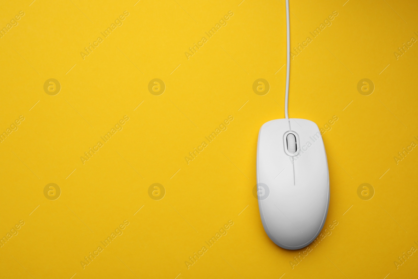 Photo of Wired computer mouse on yellow background, top view. Space for text