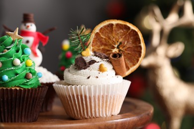Photo of Different Christmas cupcakes on wooden stand, closeup