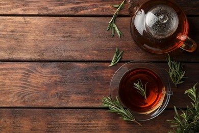 Aromatic herbal tea with rosemary on wooden table, flat lay. Space for text