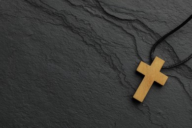 Photo of Christian cross on black table, top view. Space for text
