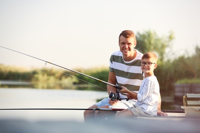 Photo of Dad and son fishing together on sunny day