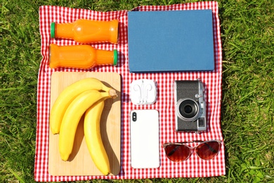 Photo of Flat lay composition with food, phone and camera on blanket in park. Summer picnic