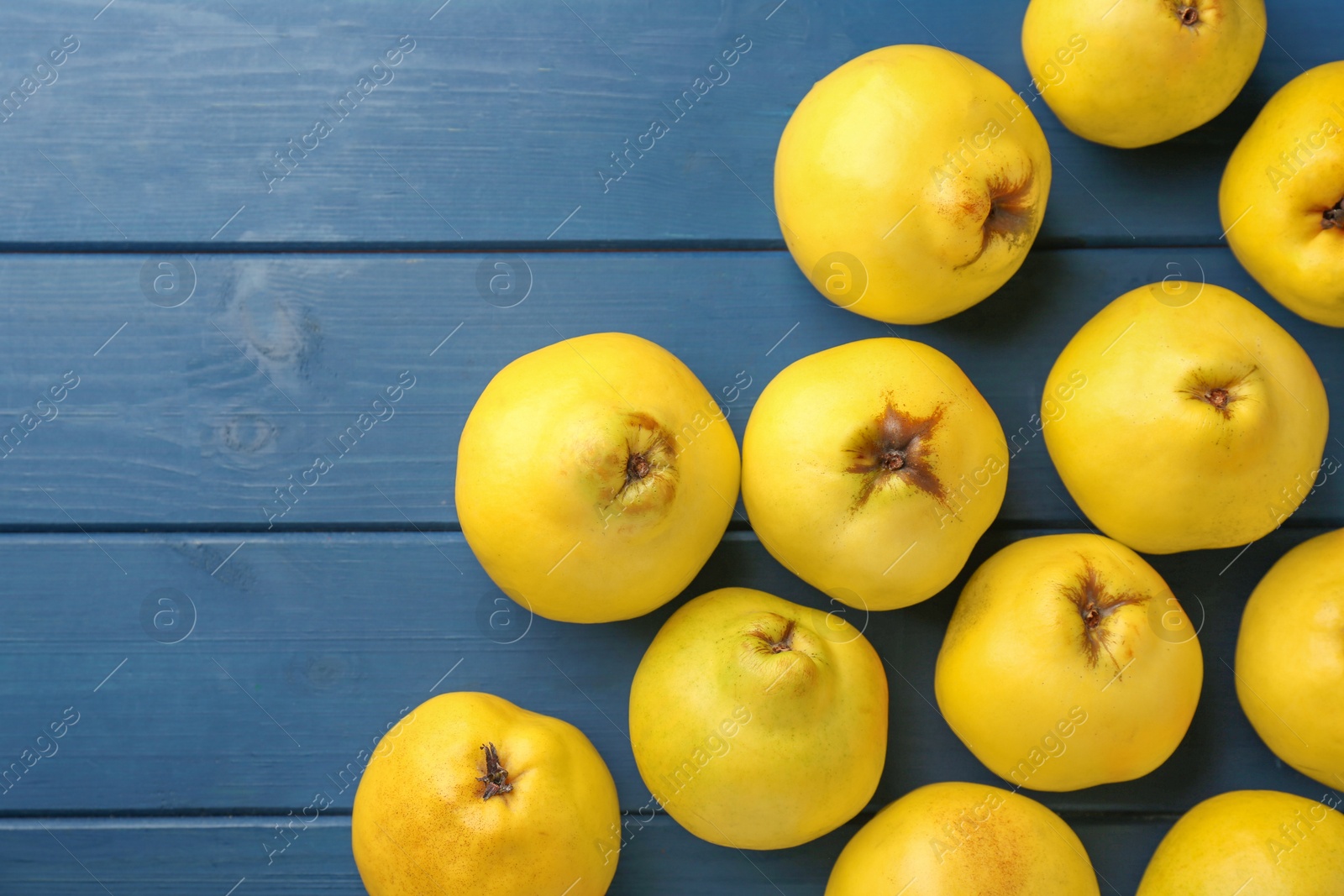 Photo of Tasty ripe quinces on blue wooden table, flat lay. Space for text