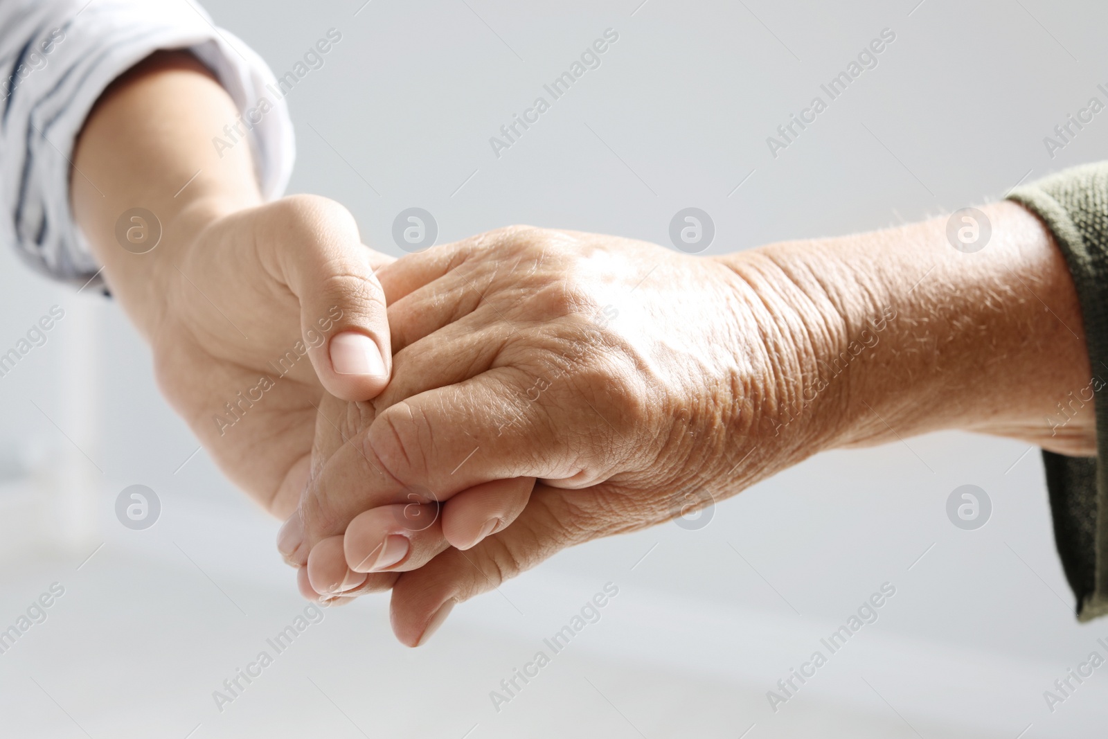 Photo of Helping hands on grey background, closeup. Elderly care concept