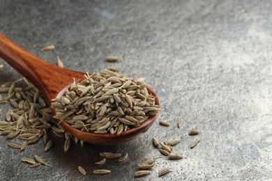 Spoon with caraway seeds on grey table, closeup. Space for text