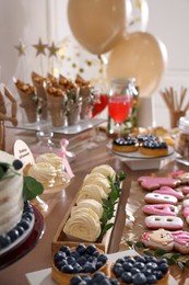Photo of Baby shower party. Different delicious treats on wooden table indoors